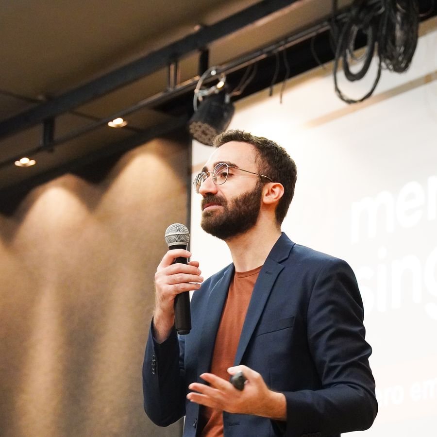 Mateus Cavarzan falando ao microfone durante a palestra