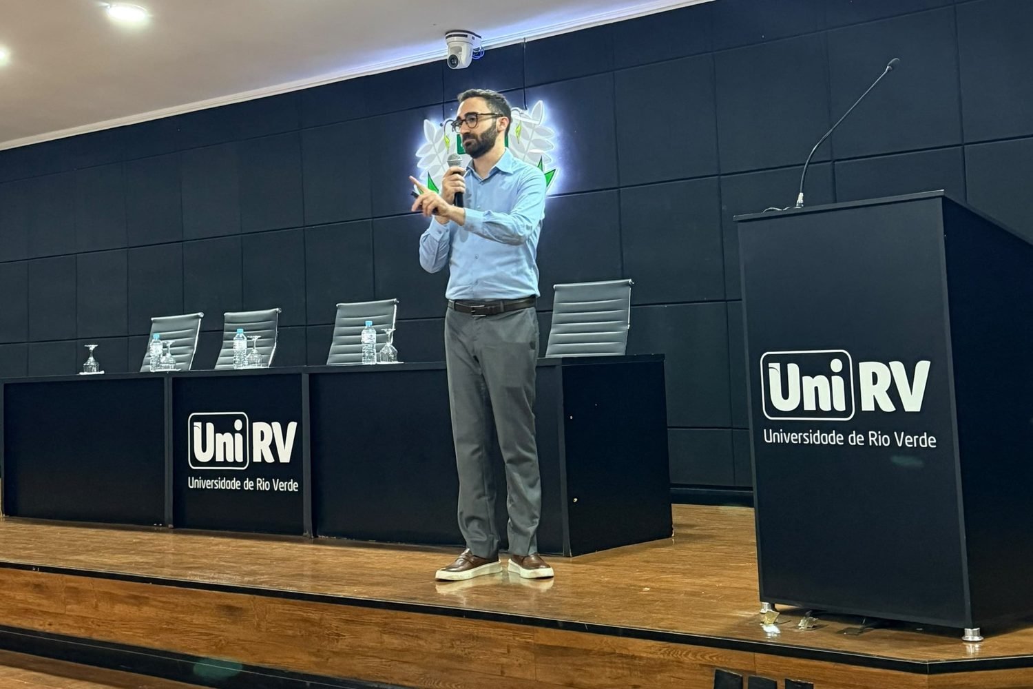 Mateus Cavarzan falando ao microfone no palco da UniRV