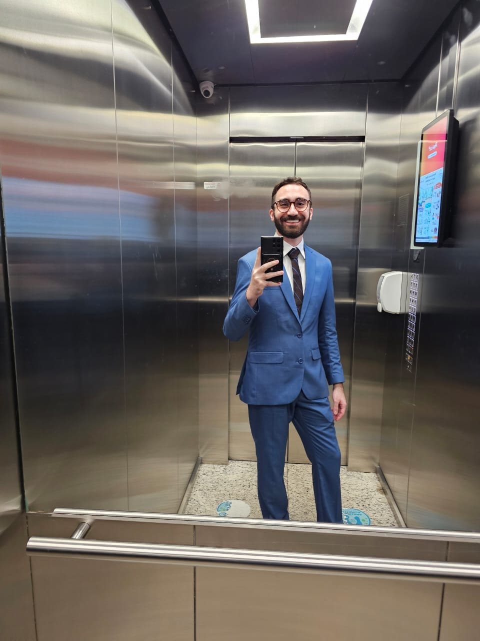 Mateus de terno azul no espelho do elevador